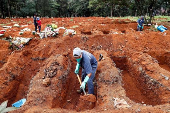 Sepultureros del cementerio de Vila Formosa, el más grande de América Latina, exhuman viejas fosas este lunes para abrir nuevos espacios a los fallecidos por COVID-19, en Sao Paulo (Brasil).