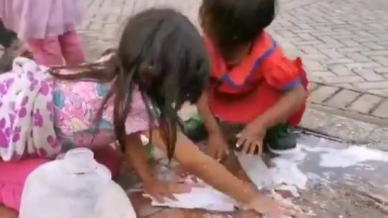 Niños indígenas lavan su tapabocas en una calle de Bogotá