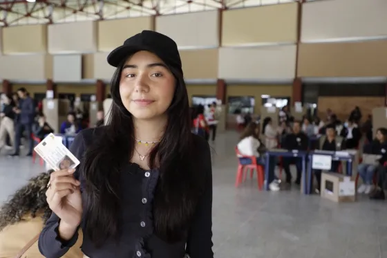 Joven muestra su documento de identidad en un puesto de votación durante la jornada electoral en Colombia. La fotografía ilustra la convocatoria de la Registraduría Nacional para que más de 11 millones de jóvenes participen en las elecciones de los Consejos de Juventud.