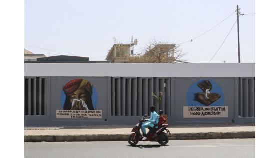 Un grupo de personas camina junto a un set de graffitis que representan los pasos higiénicos, que se deben seguir para luchar contra COVID-19 en Dakar, Senegal.  Foto: Alaattin Doğru/ Anadolu