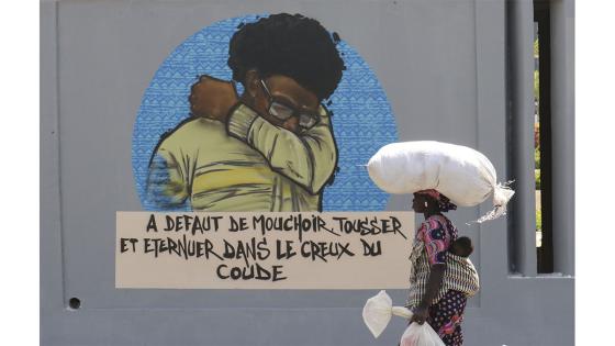 Un grupo de personas camina junto a un set de graffitis que representan los pasos higiénicos, que se deben seguir para luchar contra COVID-19 en Dakar, Senegal.  Foto: Alaattin Doğru/ Anadolu