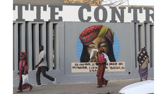 Un grupo de personas camina junto a un set de graffitis que representan los pasos higiénicos, que se deben seguir para luchar contra COVID-19 en Dakar, Senegal.  Foto: Alaattin Doğru/ Anadolu