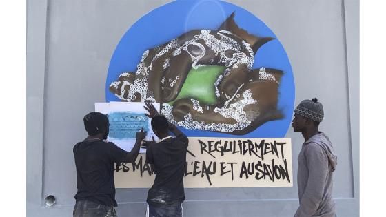 Un grupo de personas camina junto a un set de graffitis que representan los pasos higiénicos, que se deben seguir para luchar contra COVID-19 en Dakar, Senegal.  Foto: Alaattin Doğru/ Anadolu