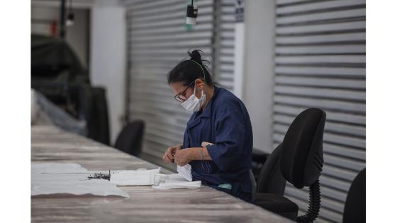 Un grupo de mujeres que forman parte de la fábrica de uniformes de la Policía Nacional pasó de fabricar uniformes a hacer tapabocas y trajes de bioseguridad.  Foto: Juancho Torres - Anadolu