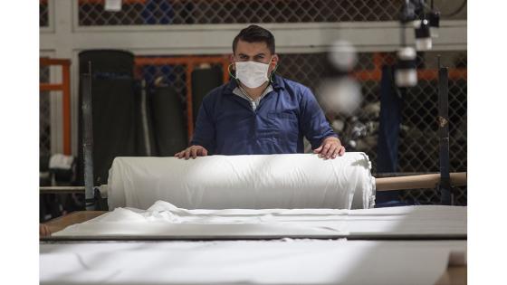 Un grupo de mujeres que forman parte de la fábrica de uniformes de la Policía Nacional pasó de fabricar uniformes a hacer tapabocas y trajes de bioseguridad.  Foto: Juancho Torres - Anadolu