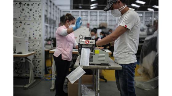 Un grupo de mujeres que forman parte de la fábrica de uniformes de la Policía Nacional pasó de fabricar uniformes a hacer tapabocas y trajes de bioseguridad.  Foto: Juancho Torres - Anadolu