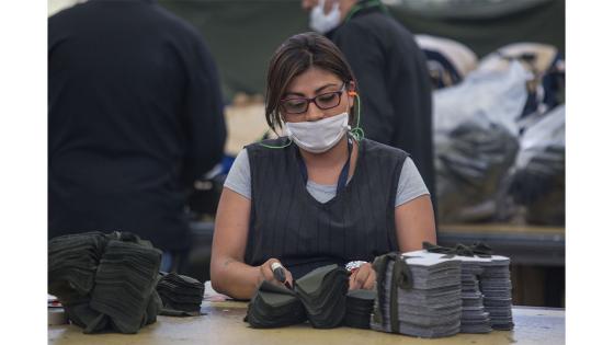 Un grupo de mujeres que forman parte de la fábrica de uniformes de la Policía Nacional pasó de fabricar uniformes a hacer tapabocas y trajes de bioseguridad.  Foto: Juancho Torres - Anadolu