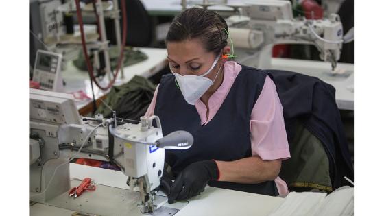 Un grupo de mujeres que forman parte de la fábrica de uniformes de la Policía Nacional pasó de fabricar uniformes a hacer tapabocas y trajes de bioseguridad.  Foto: Juancho Torres - Anadolu