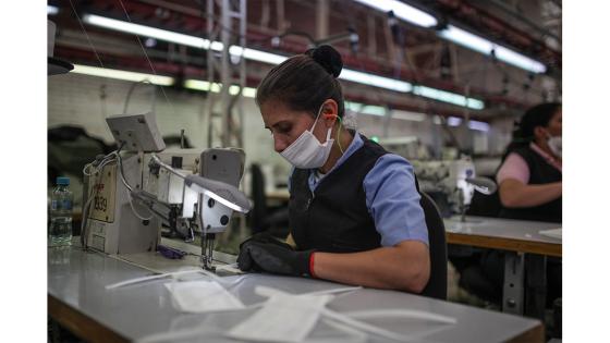 Un grupo de mujeres que forman parte de la fábrica de uniformes de la Policía Nacional pasó de fabricar uniformes a hacer tapabocas y trajes de bioseguridad.  Foto: Juancho Torres - Anadolu