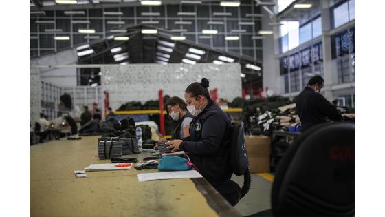 Un grupo de mujeres que forman parte de la fábrica de uniformes de la Policía Nacional pasó de fabricar uniformes a hacer tapabocas y trajes de bioseguridad.  Foto: Juancho Torres - Anadolu